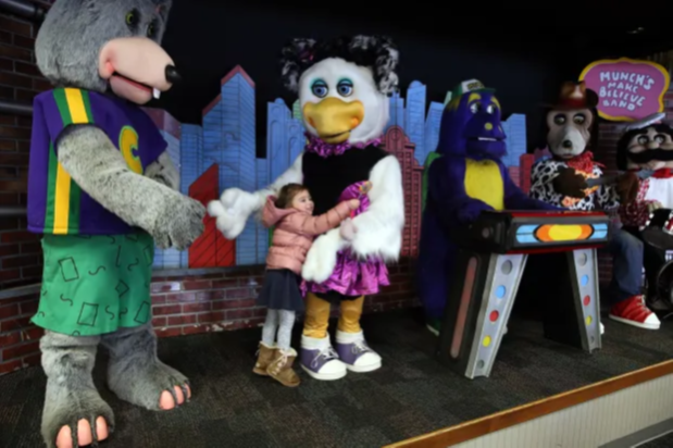 A child hugs Chuck E. Cheese animatronics